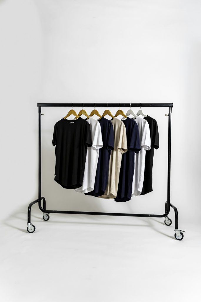 Black, white and neutral t-shirts hanging on a clothing rail in a bright studio