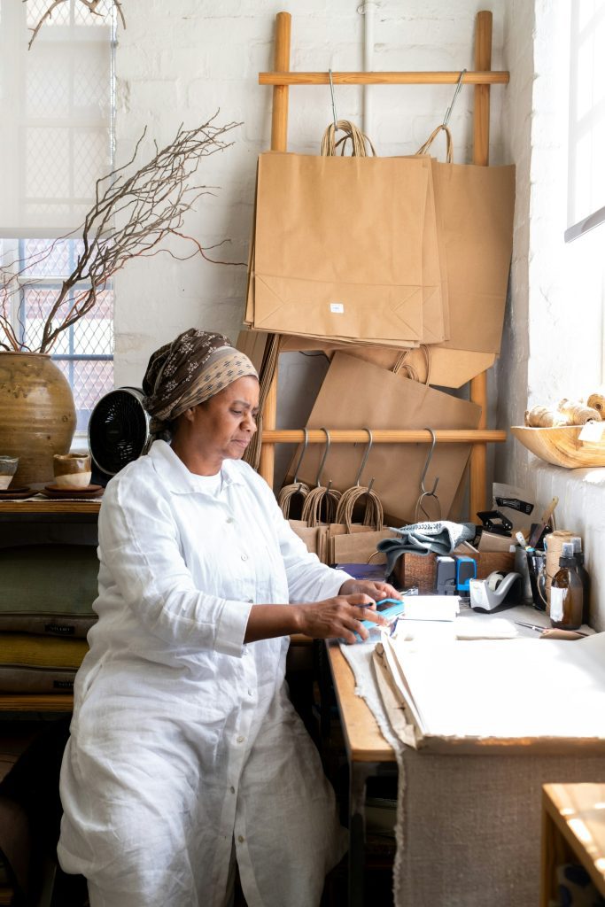 Maker working at a desk in a small product studio with paper bags and supplies